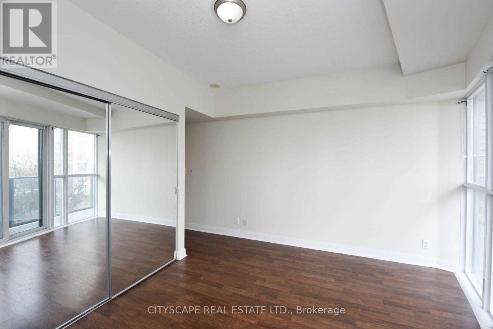 A spacious room with wood flooring and a sliding glass door.