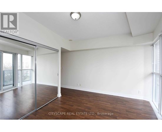 A spacious room with wood flooring and a sliding glass door.