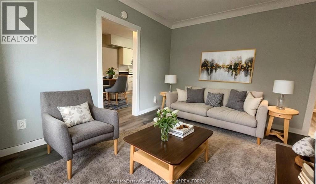 A living room with a grey couch, a grey armchair, a wooden coffee table, and a painting on the wall.