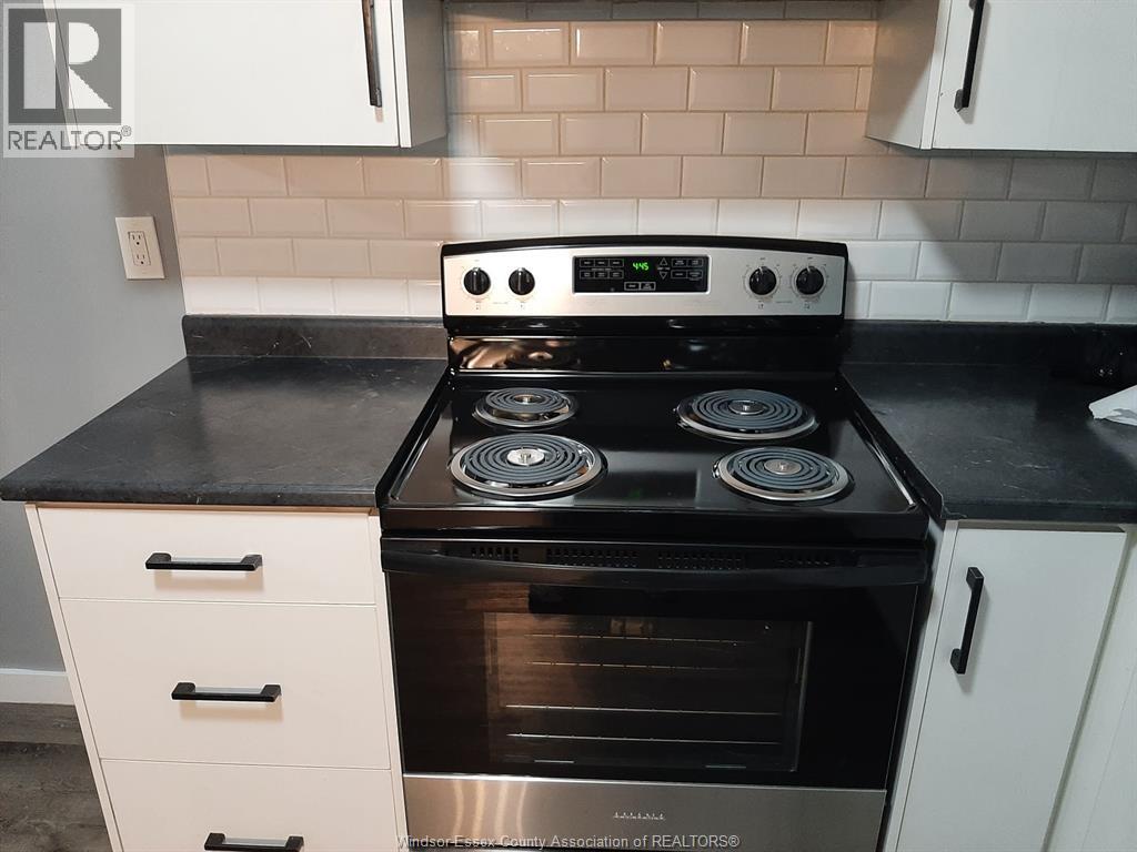 A modern kitchen with a black countertop and a stove with four burners.