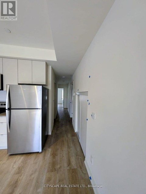 A kitchen with a refrigerator and cabinets in a house.