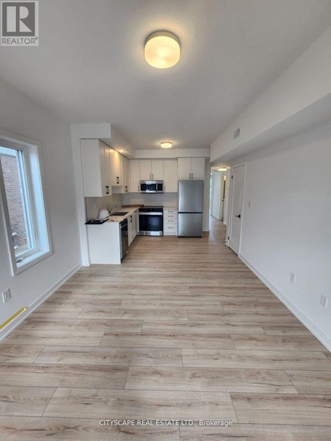 A kitchen with white cabinets and a wooden floor.