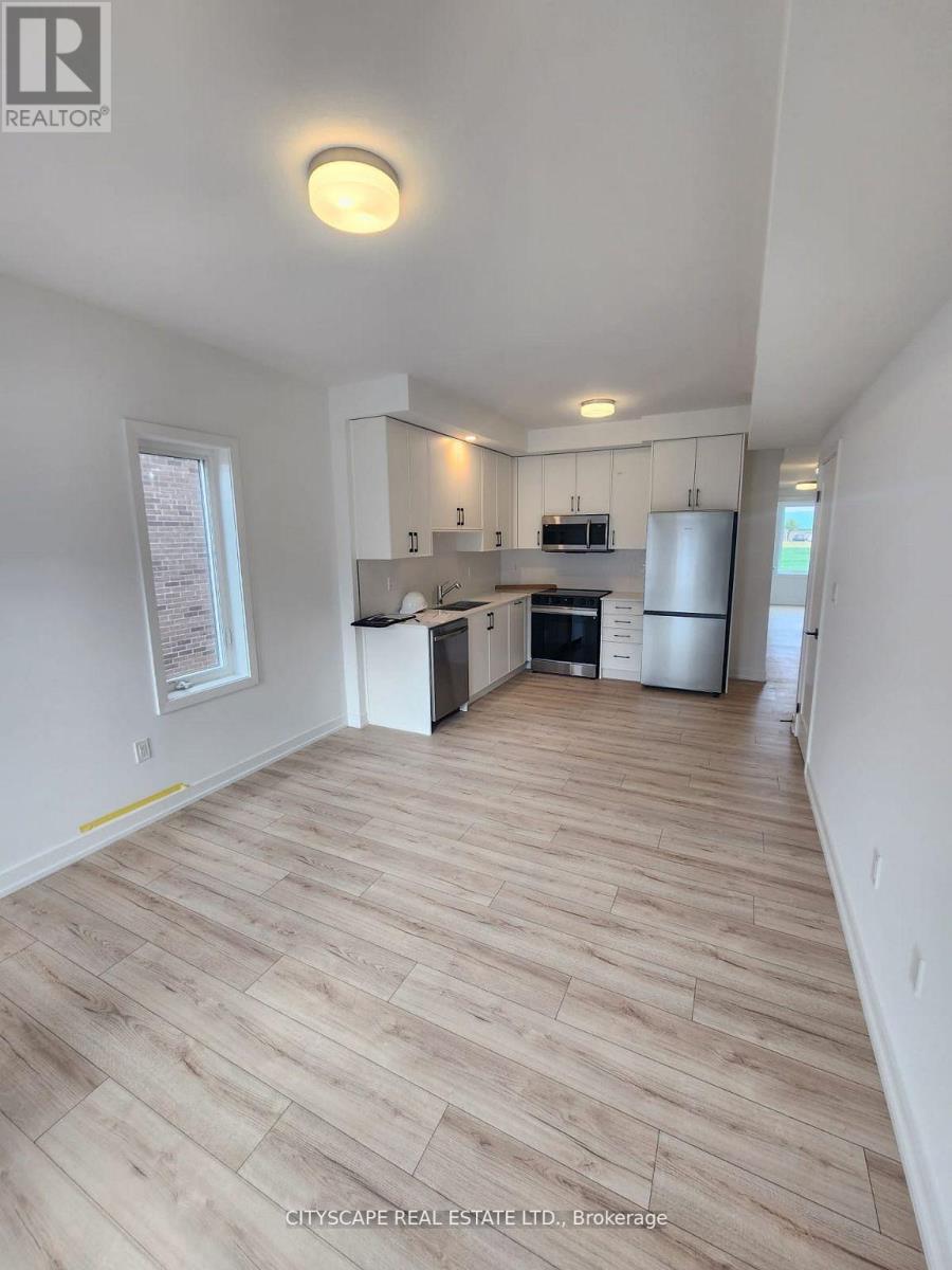 A spacious kitchen with white cabinets and a wooden floor.