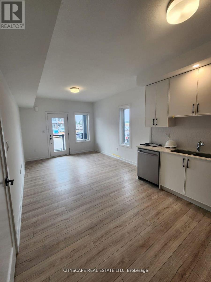 A real estate listing image of a kitchen and living room with wood flooring.