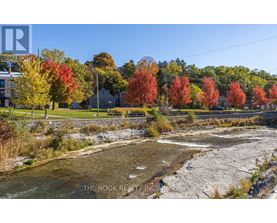A river flows through a rocky bed with autumn trees in the background.