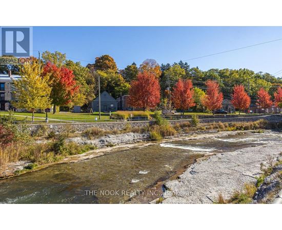 A river flows through a rocky bed with autumn trees in the background.