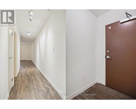 A hallway with a brown door and white walls.