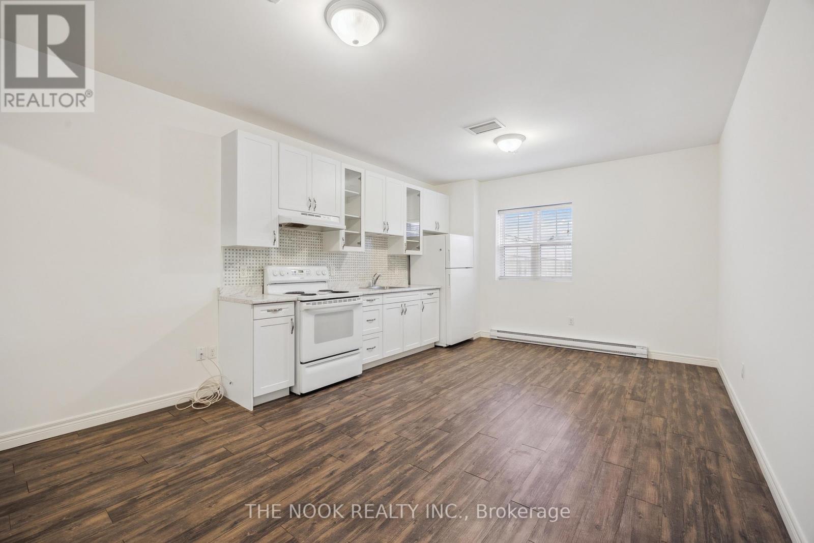 A kitchen with white cabinets and a wooden floor.