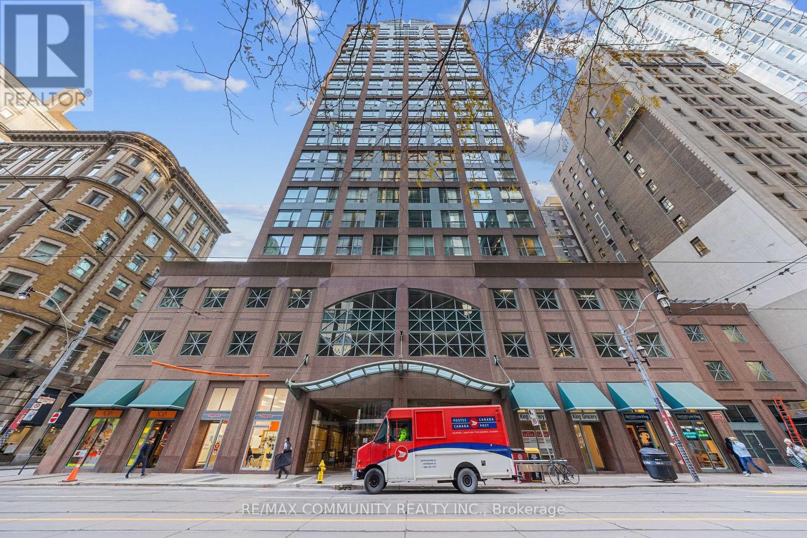 A red and white bus is parked in front of a building with a large glass facade.