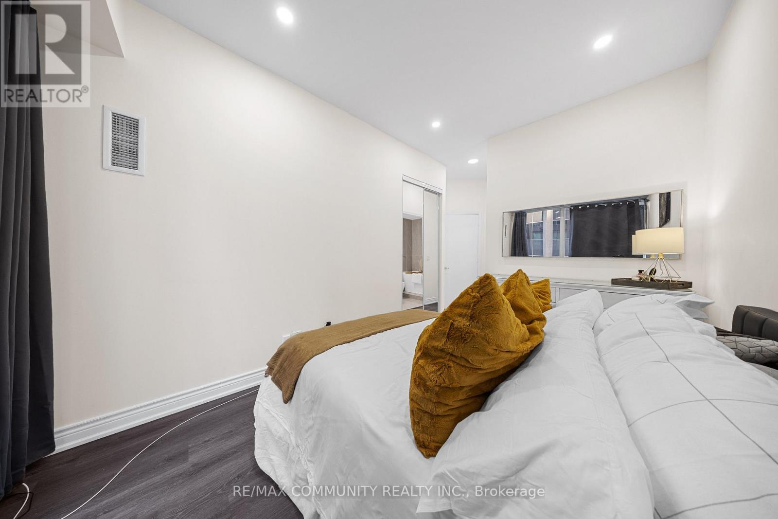 A bedroom with a large bed and a window with curtains.