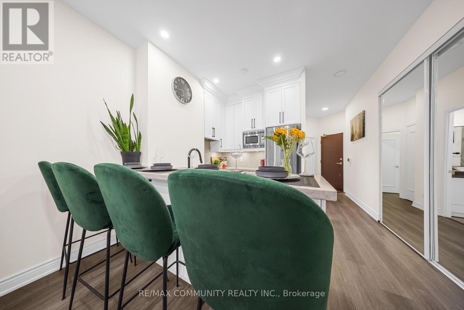A dining room with green chairs and a white wall.