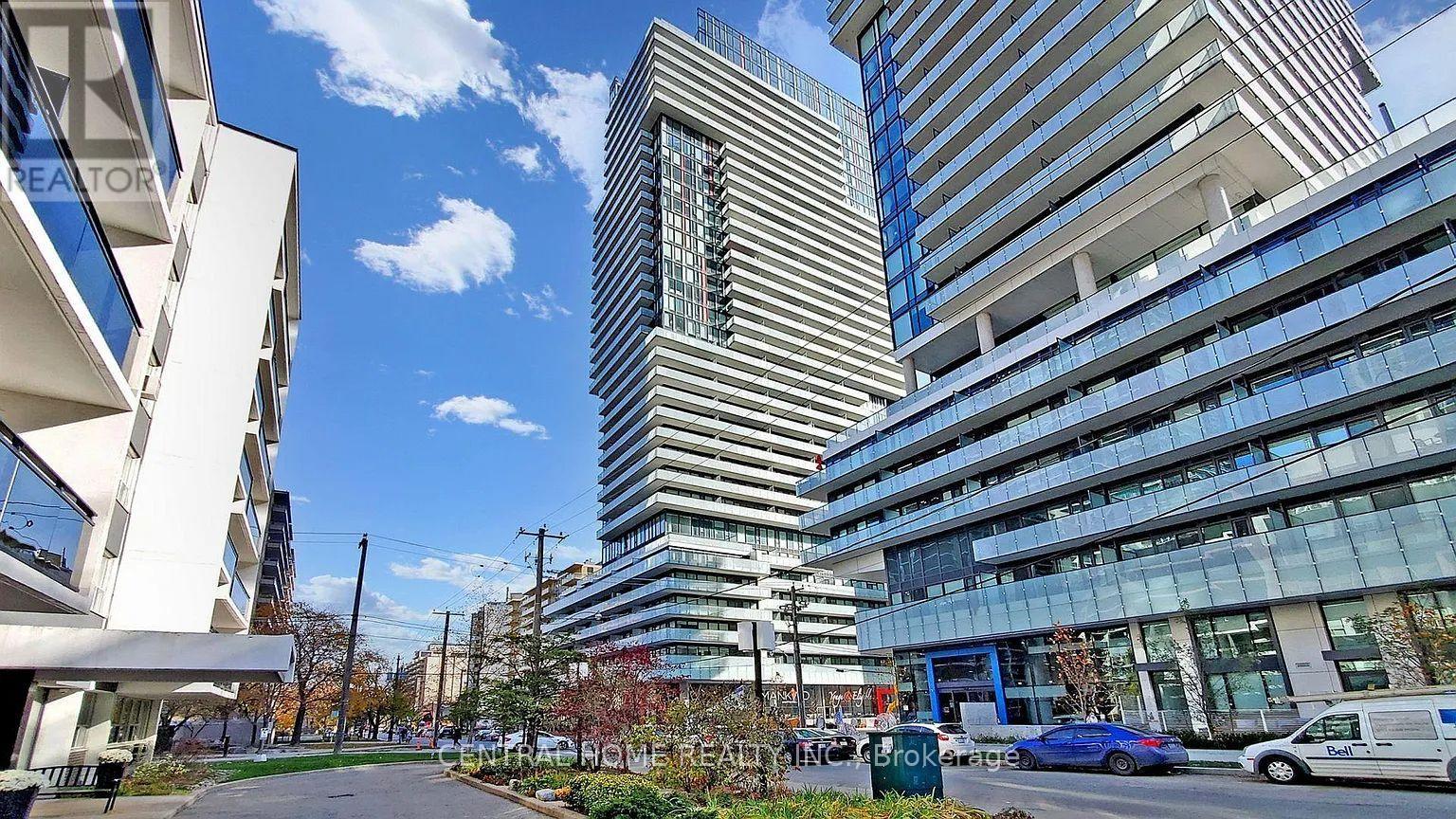 A modern building with a curved glass facade stands in front of other buildings.