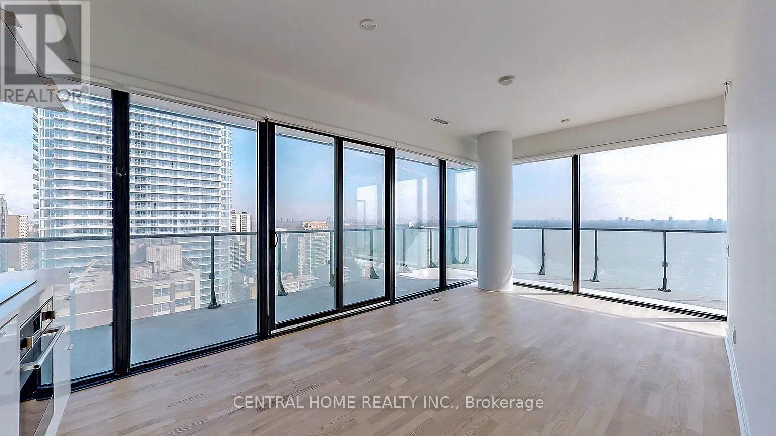 A spacious room with a view of the cityscape through large windows.