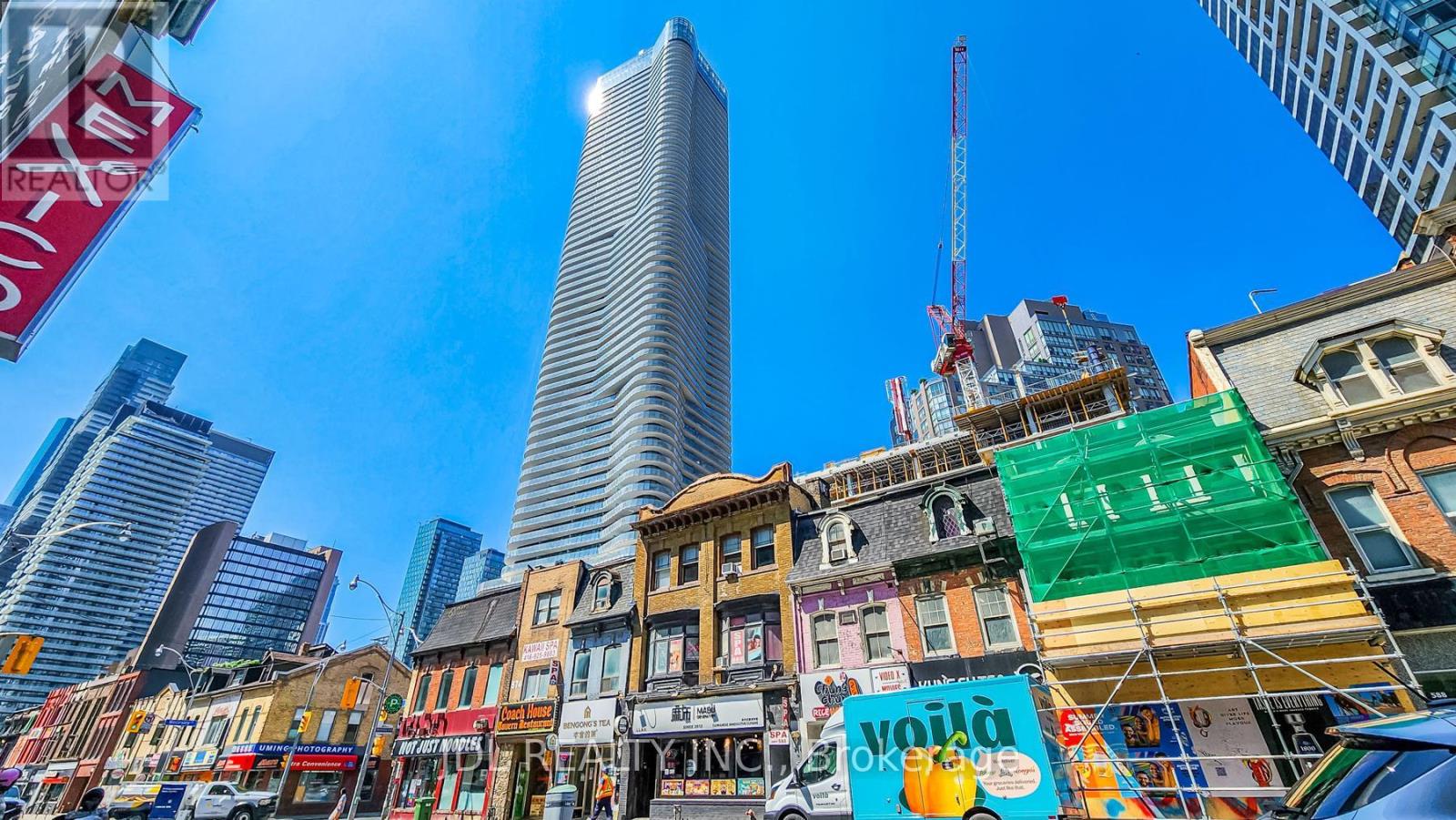 A city street with a mix of old and new buildings, with a clear blue sky above.