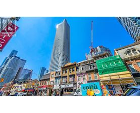 A city street with a mix of old and new buildings, with a clear blue sky above.