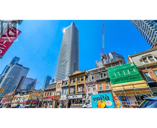 A city street with a mix of old and new buildings, with a clear blue sky above.