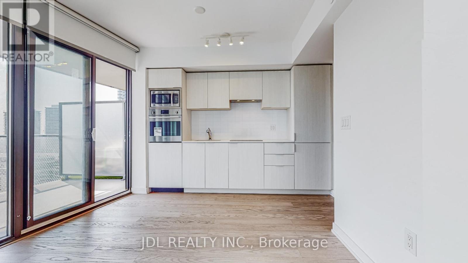A modern kitchen with white cabinets and a wooden floor.