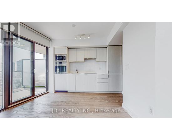 A modern kitchen with white cabinets and a wooden floor.
