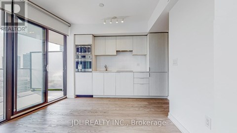 A modern kitchen with white cabinets and a wooden floor.
