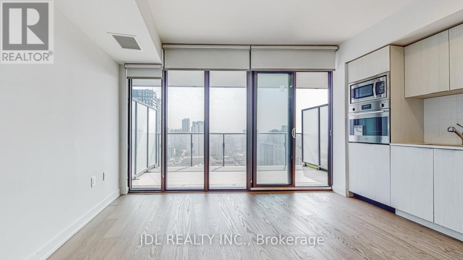 A modern kitchen with white cabinets and a view of the city through the glass doors.