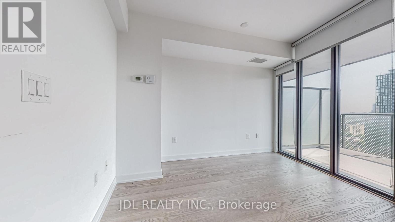 A spacious room with a sliding glass door leading to a balcony.