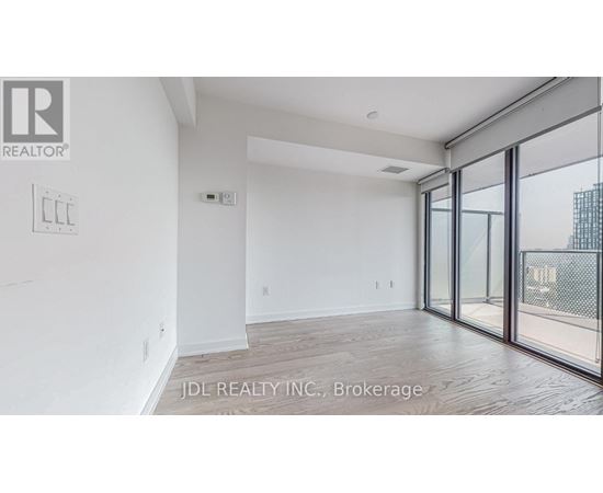 A spacious room with a sliding glass door leading to a balcony.