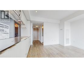 A spacious room with wooden flooring and white walls, part of a real estate listing.