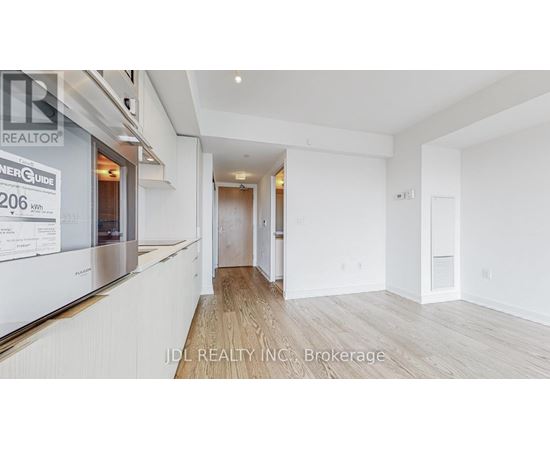 A spacious room with wooden flooring and white walls, part of a real estate listing.