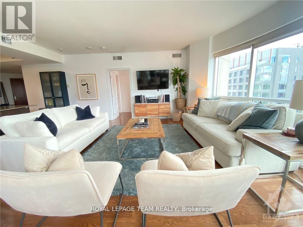A living room with white furniture and a flat screen TV.
