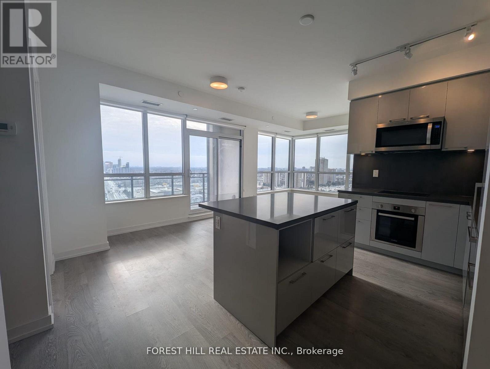 A modern kitchen with a large island and a view of the city.