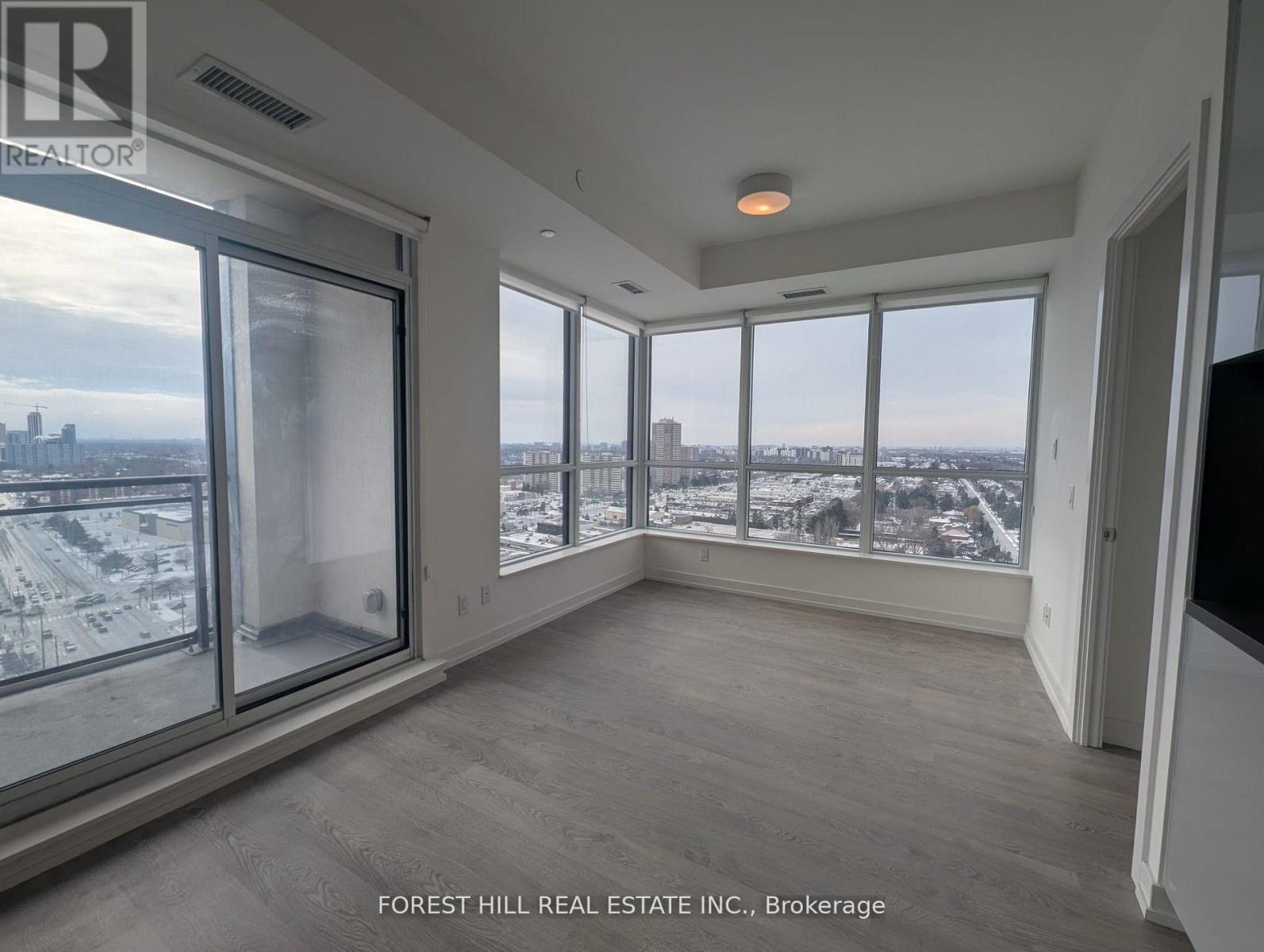 A spacious room with a view of the cityscape through large windows.