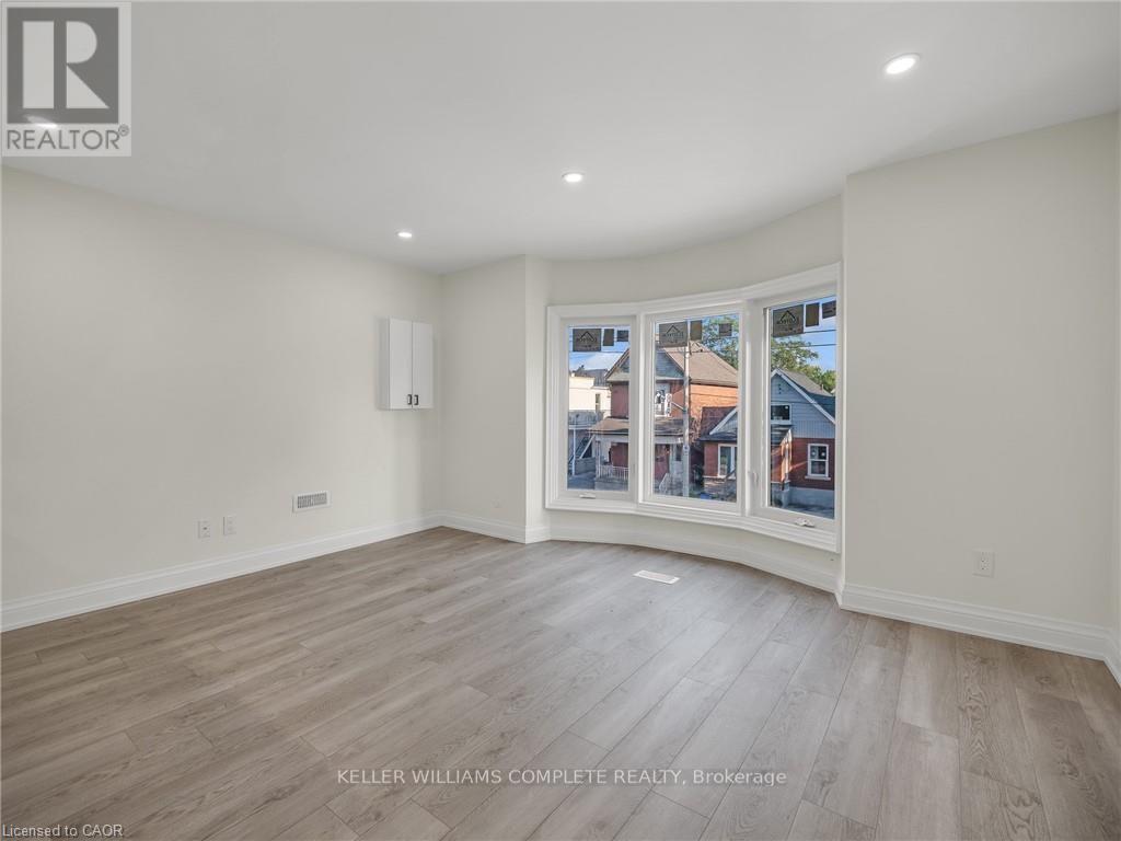 A room with a large window showing a view of houses outside.