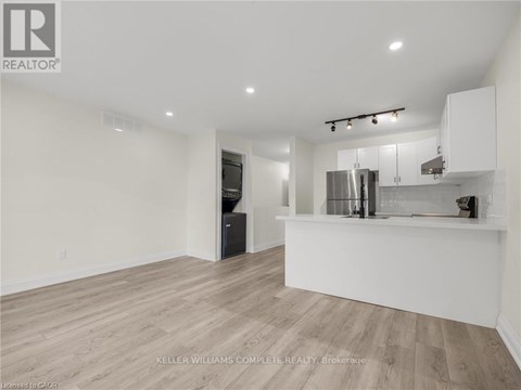 A spacious kitchen with white cabinets and a wooden floor.