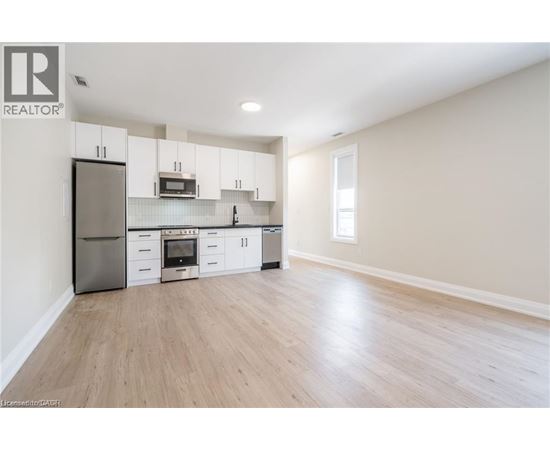 A kitchen with white cabinets and a wooden floor.