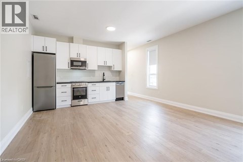 A kitchen with white cabinets and a wooden floor.