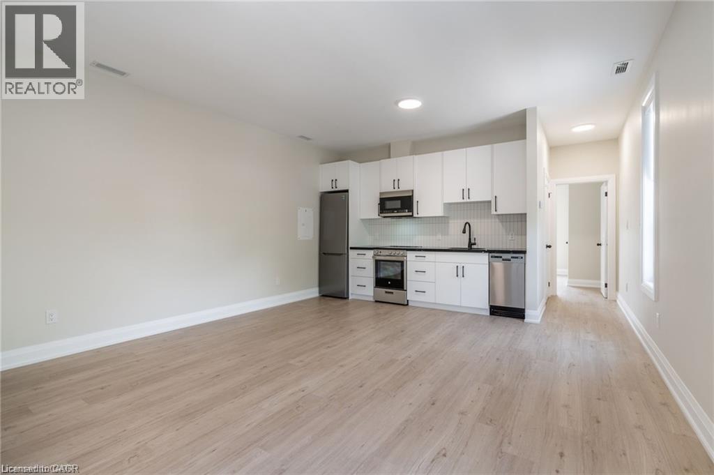 A spacious kitchen with white cabinets and a wooden floor.