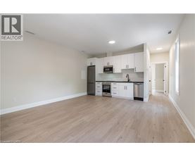 A spacious kitchen with white cabinets and a wooden floor.