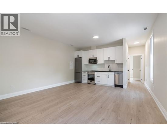 A spacious kitchen with white cabinets and a wooden floor.