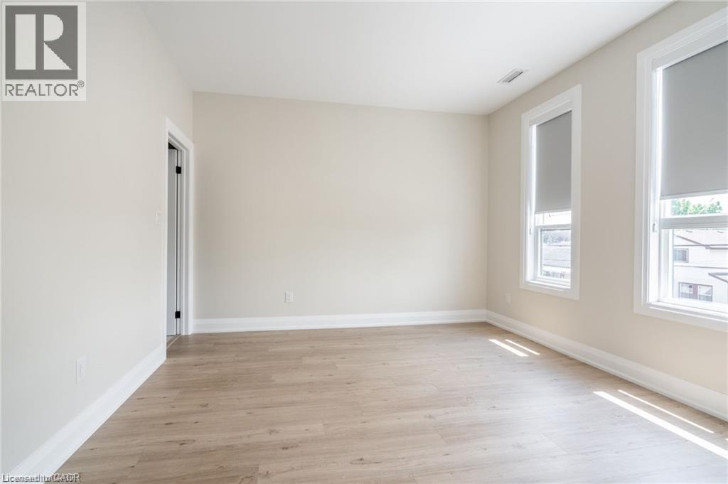 A spacious room with wooden flooring and a window on the right side.
