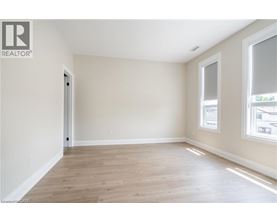 A spacious room with wooden flooring and a window on the right side.