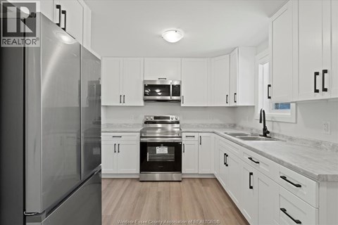 A kitchen with white cabinets and a stainless steel refrigerator.