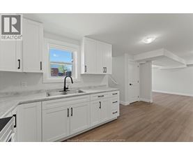 A kitchen with white cabinets and a marble countertop.