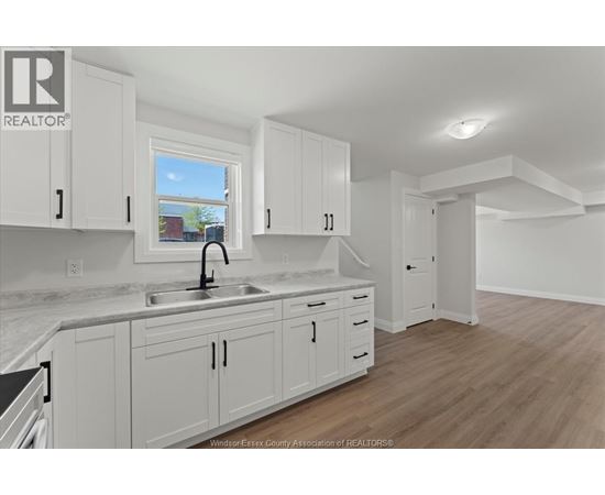 A kitchen with white cabinets and a marble countertop.
