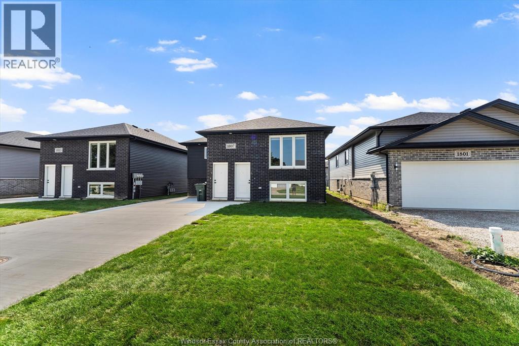 A realtor photo of a house with a well-maintained lawn and a clear sky.