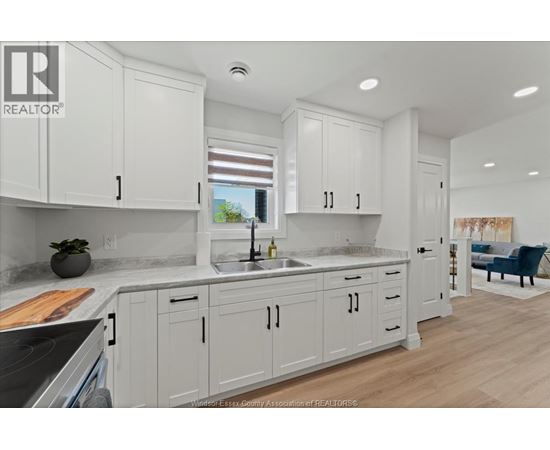 A kitchen with white cabinets and a marble countertop.
