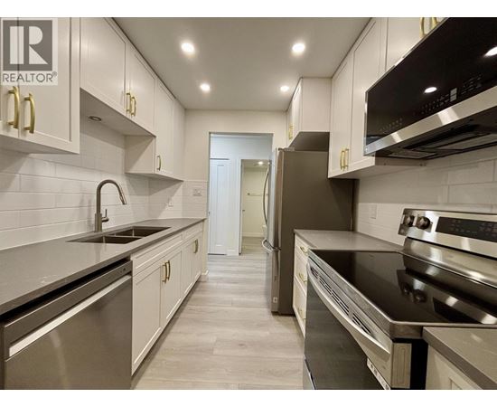 A modern kitchen with stainless steel appliances and white cabinets.