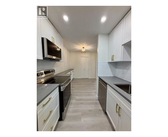 A well-lit kitchen with white cabinets and a grey floor.