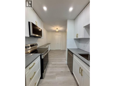 A well-lit kitchen with white cabinets and a grey floor.