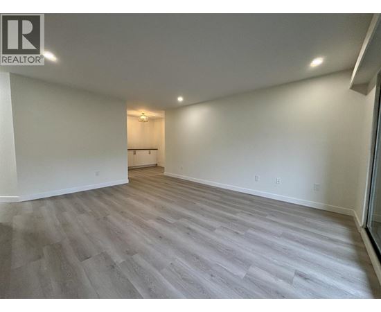 A spacious room with wooden flooring and white walls.