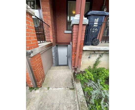 A small door is on the side of a brick building.